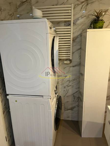 Pračka se sušičkou v koupelně 4pokojového bytu, mramorový obklad na stěnách.