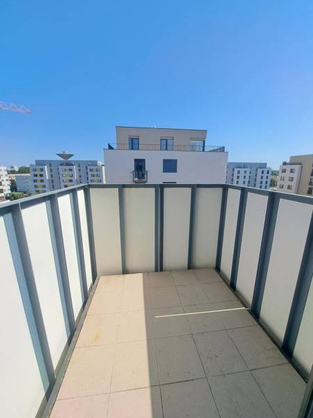 Balkon 2-pokojového bytu v Galantě s výhledem na moderní budovy a modrou oblohu.