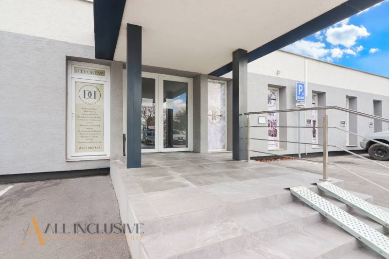 Vchod obchodních prostor na ulici Vajanského, s bezbariérovým přístupem a parkovacím místem.