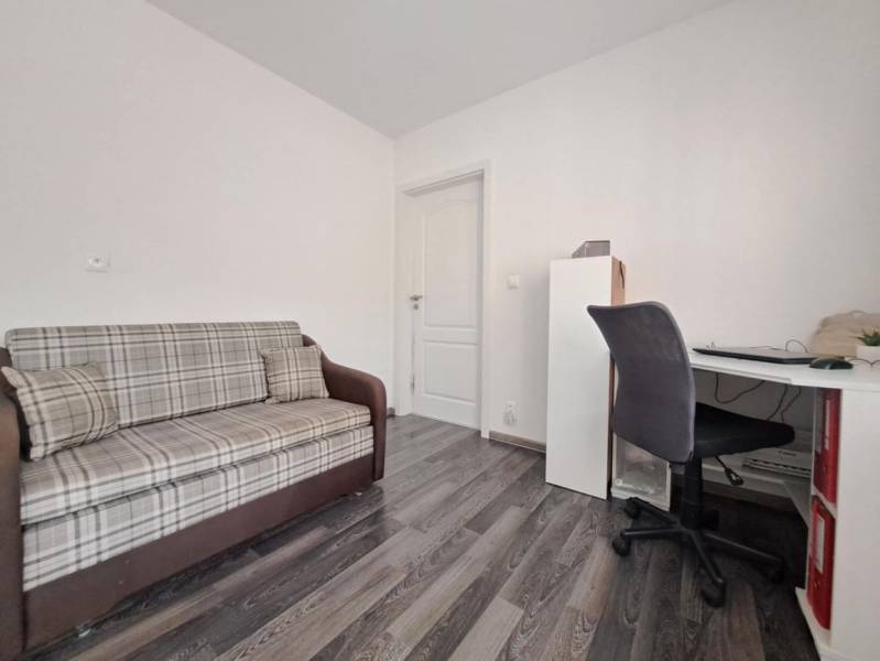 Pohovka a pracovní stůl v rodinném domě s podlahou s dřevěným dekorem.