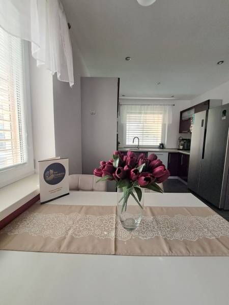 Kuchyně v rodinném domě s váhou tulipánů na stole a bílými závěsy.