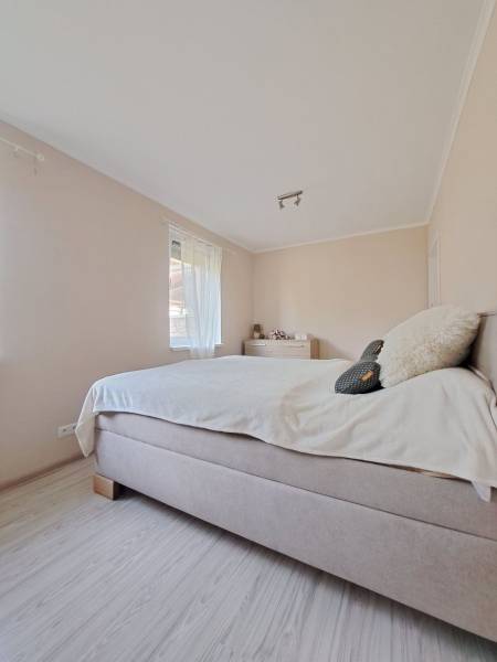 Světlá ložnice v rodinném domě s pohodlnou postelí a podlahou s dřevěným dekorem.