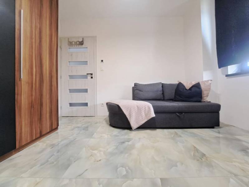 Pokoj v rodinném domě s pohovkou, skříňkou, dveřmi a podlahou s mramorovým dekorem.