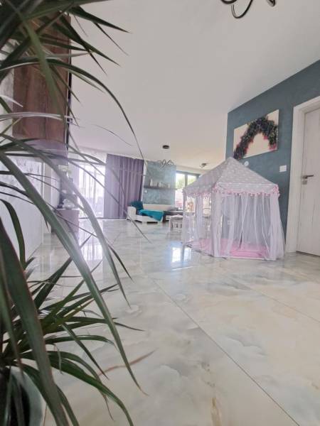 Interiér rodinného domu se stanem pro děti na lesklé podlaze a rostlinami.