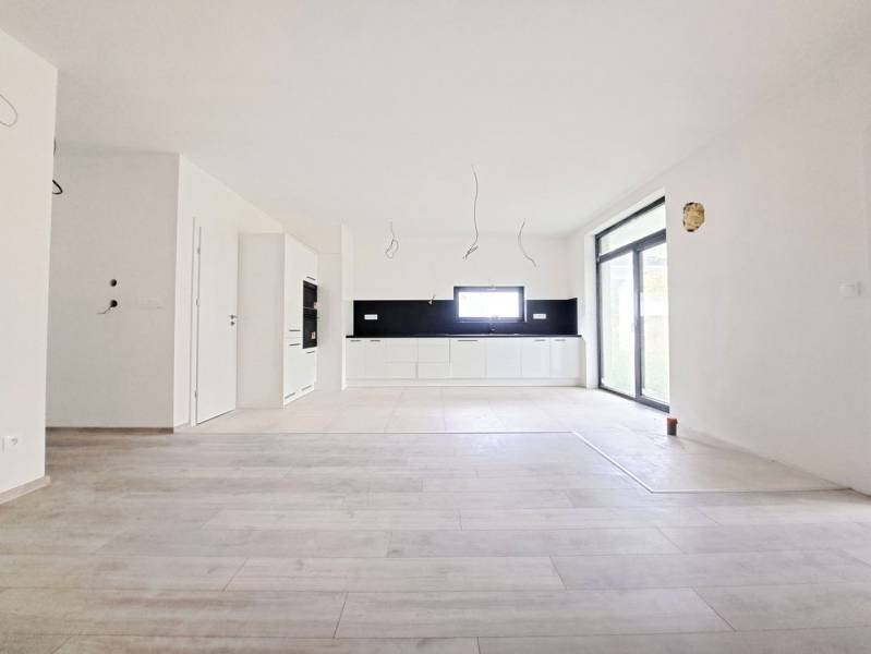 Prostorná kuchyně s černým obkladem a podlahou s dřevěným dekorem v rodinném domě.