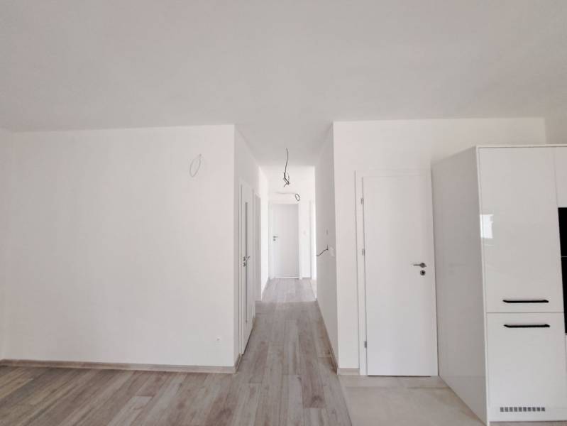 Světlý interiér rodinného domu s podlahou s dřevěným dekorem a bílými stěnami.