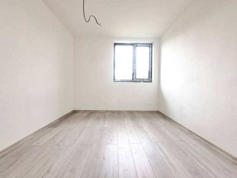 Prázdná místnost s podlahou s dřevěným dekorem a oknem v rodinném domě.