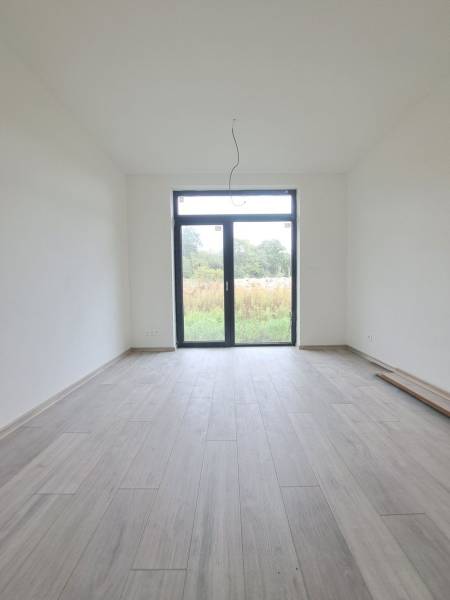 Interiér rodinného domu s podlahou s dřevěným dekorem a velkým oknem.