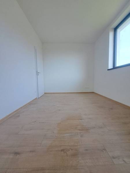 Interiér rodinného domu se světlou místností, podlaha s dřevěným dekorem, velké okno.