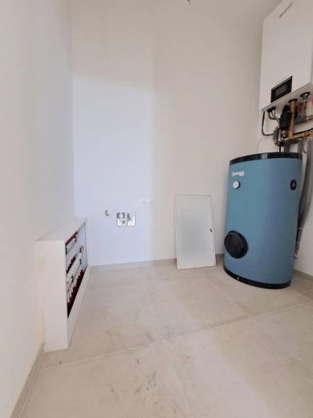 Kotelně v rodinném domě s bojlery a rozvody na světlé podlaze.