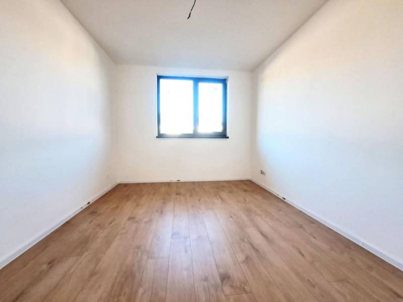 Výhled na pokoj s bílými stěnami a podlahou s dřevěným dekorem v rodinném domě.