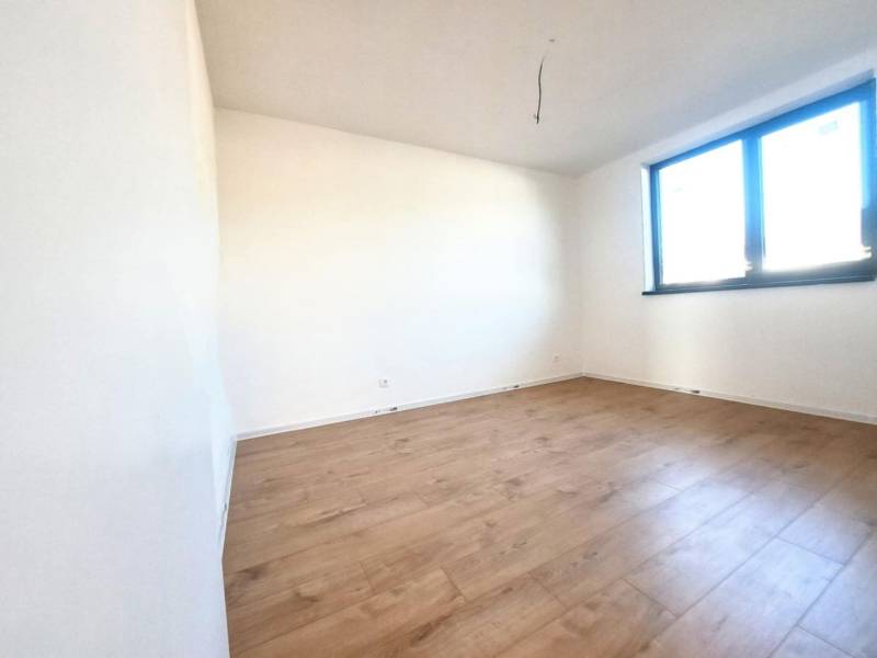 Prázdná místnost s podlahou s dřevěným dekorem a velkým oknem v rodinném domě.