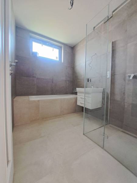 Koupelna v rodinném domě s vanou, sprchovým koutem a umyvadlem.