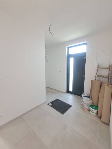 Vstupní hala rodinného domu s dlažbou, vedle dveří je schůdek a materiál.