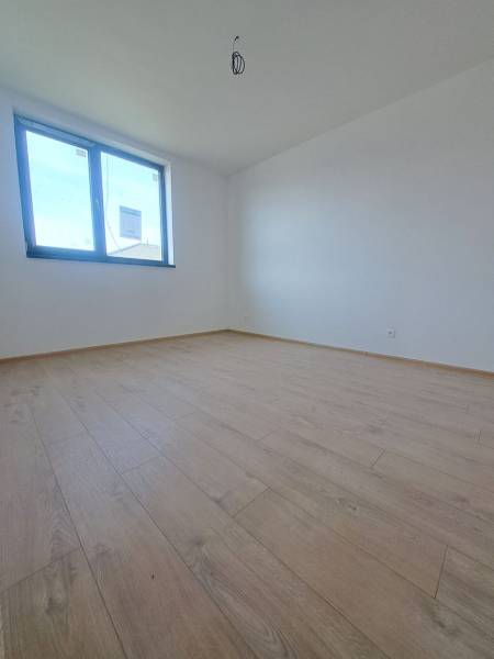 Pokoj v rodinném domě s podlahou s dřevěným dekorem a velkým oknem.