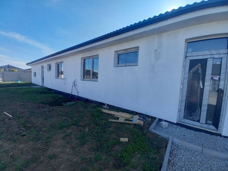 Rodinný dům v Galantě s bílou fasádou, velkými okny, rozestavěné okolí.