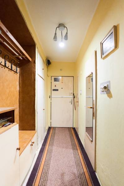 Chodba v 3-pokojovém bytě s věšákem, zrcadlem a jednoduchým osvětlením.