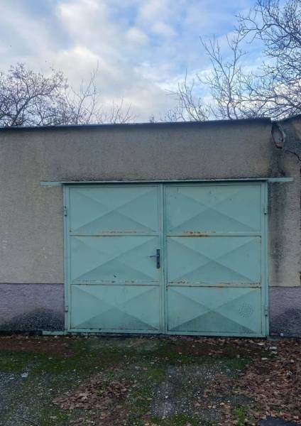 Garážová vrata se světle modrými dveřmi a opadané listí v Selicích.