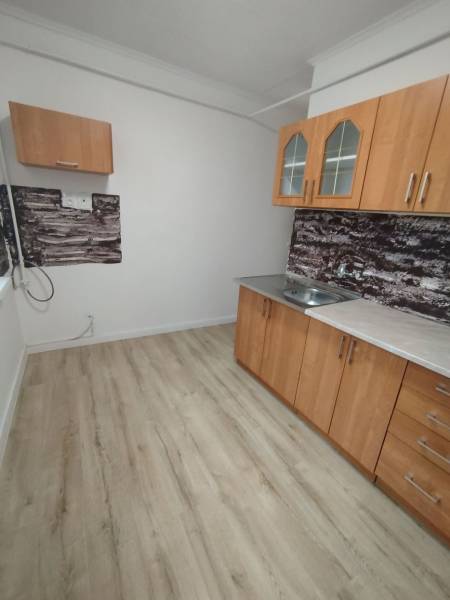 Kuchyně v 3pokojovém bytě má dřevěný dekor podlahy a jednoduché skříňky.