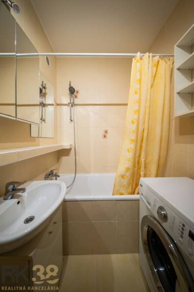Koupelna se sprchou a pračkou v 2-pokojovém bytě.