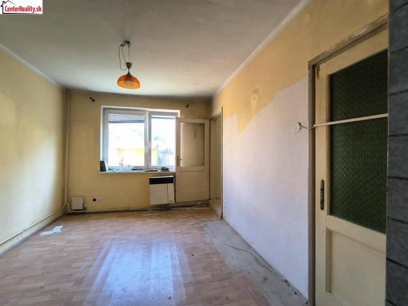 Pokoj v rodinném domě s oknem, dveřmi a podlahou.