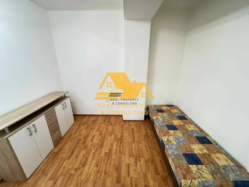 Pokoj v 3-pokojovém bytě s postelí, komodou a podlahou s dřevěným dekorem.