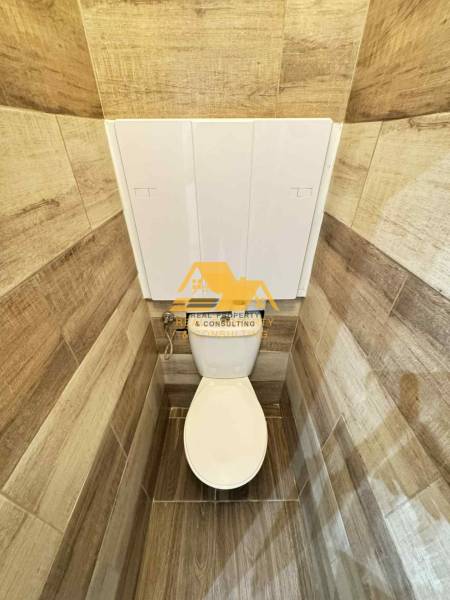 Toaleta s obklady v dekoru dřeva v 3-pokojovém bytě.