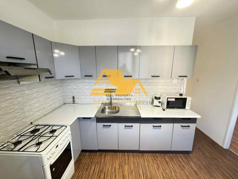 Kuchyně ve 3-pokojovém bytě s podlahou s dřevěným dekorem a moderním vybavením.