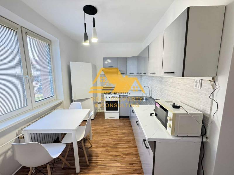 Kuchyně ve 3-pokojovém bytě s bílými skříňkami a podlahou s dřevěným dekorem.