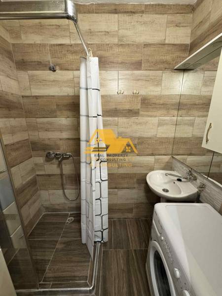 Koupelna v 3-pokojovém bytě s podlahou s dřevěným dekorem, sprchovým koutem a pračkou.