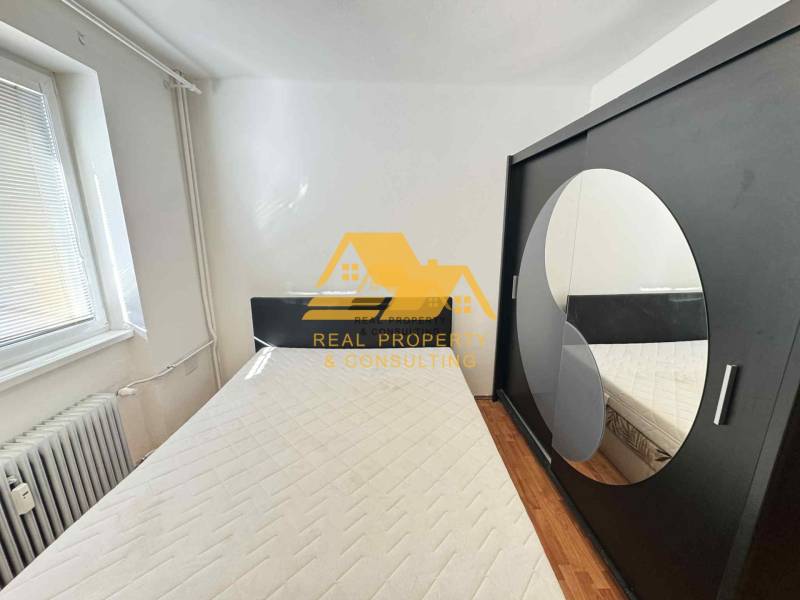 Ložnice v 3-pokojovém bytě s postelí, skříní a podlahou s dřevěným dekorem.