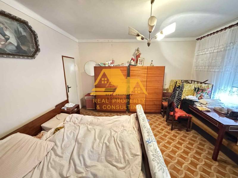 Ložnice v rodinném domě s postelí, skříní a kobercem s geometrickým vzorem.