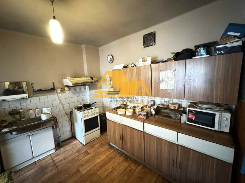 Kuchyně v rodinném domě s dřevěným dekorem podlahy, kuchyňská linka, spotřebiče, úložné skříňky.