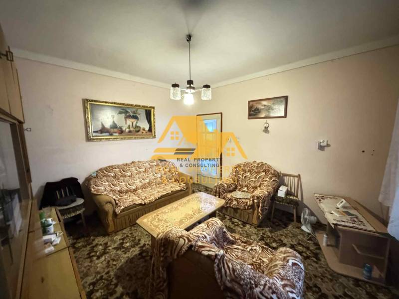 Obývací pokoj v rodinném domě s gaučem a křesly, dekorovaný obrazy.