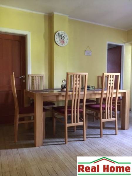 Jídelna v rodinném domě se židlemi a stolem na podlaze s dřevěným dekorem.