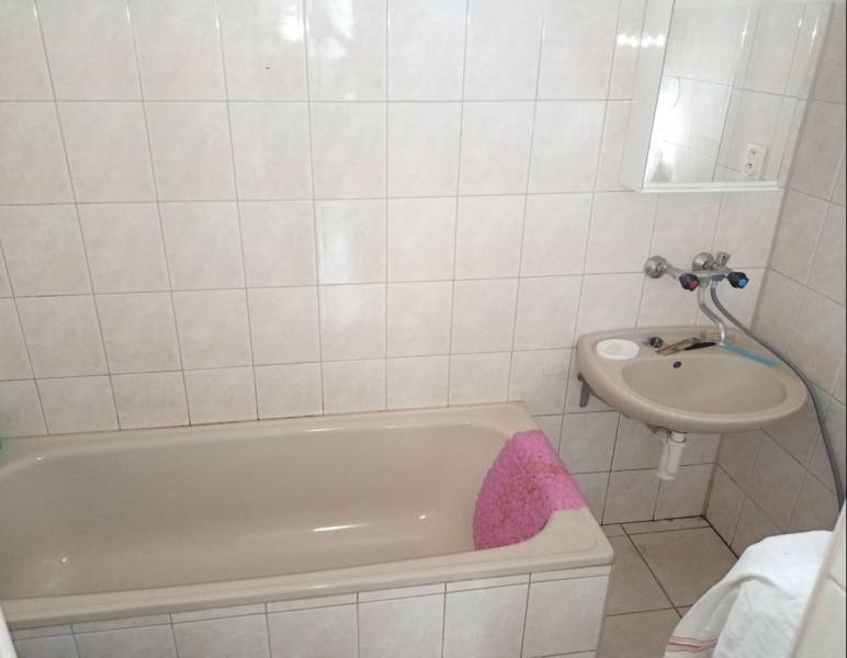 Koupelna s vanou a umyvadlem v rodinném domě, světlé obklady a dlažba.