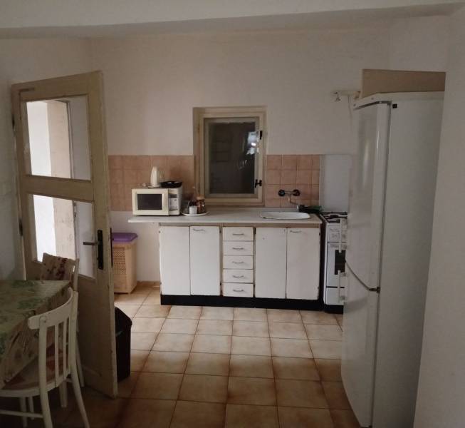 Kuchyně v rodinném domě s bílými skříňkami, mikrovlnkou a ledničkou.