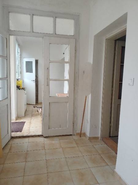 Interiér rodinného domu s bílými dveřmi a podlahou z dlaždic.