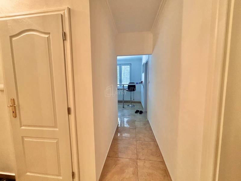 Chodba v 2-pokojovém bytě s dlažbou a otevřeným výhledem do kuchyně.