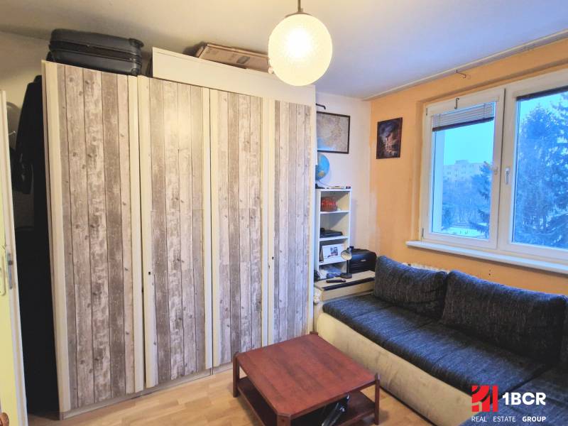 Garsonka s podlahou s dřevěným dekorem, gaučem, skříněmi a stolkem. Minimalistický interiér.