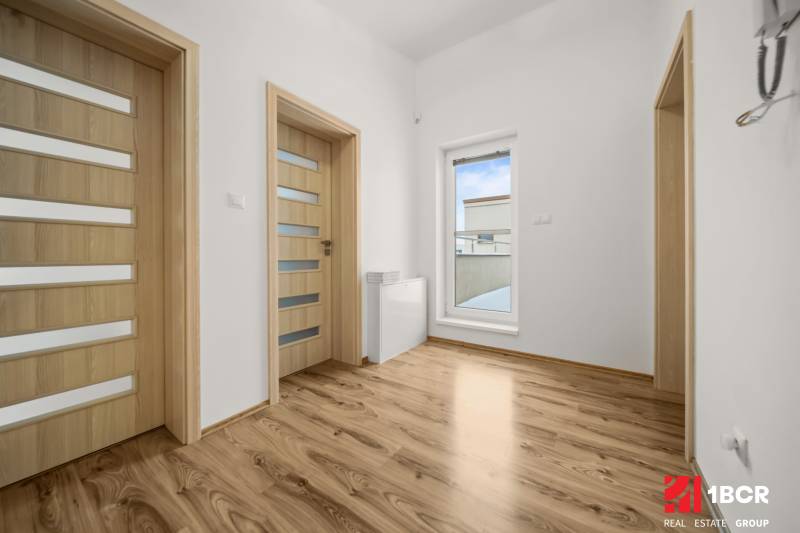 Interiér rodinného domu s podlahou s dřevěným dekorem a dveřmi s prosklením.