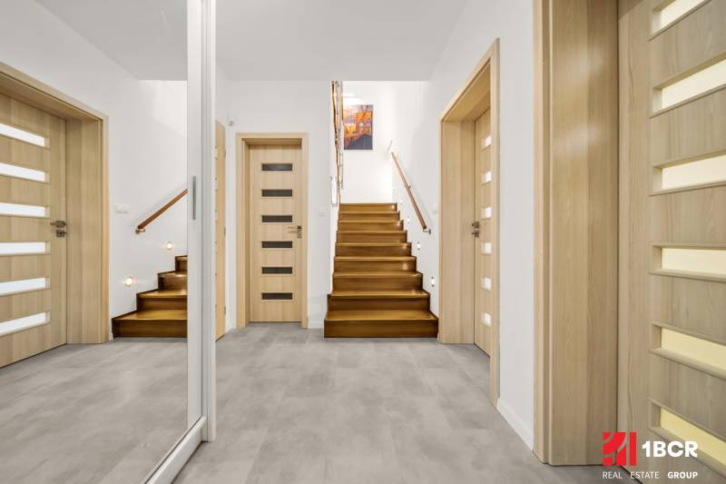 Vstupní hala v rodinném domě s podlahou s dřevěným dekorem a schodištěm.