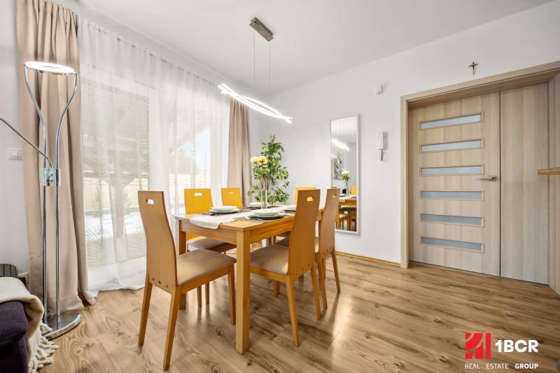 Jídelna s dřevěným stolem a podlahou s dřevěným dekorem v rodinném domě.