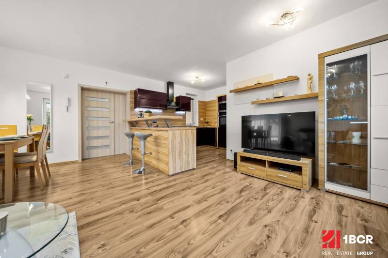 Obývací pokoj v rodinném domě s kuchyní a podlahou s dřevěným dekorem.