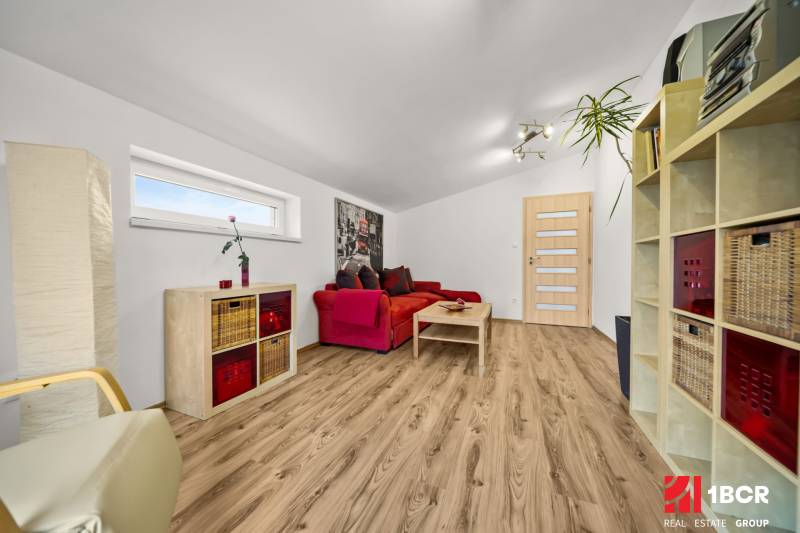 Obývací pokoj v rodinném domě s červenou sedačkou a podlahou s dřevěným dekorem.