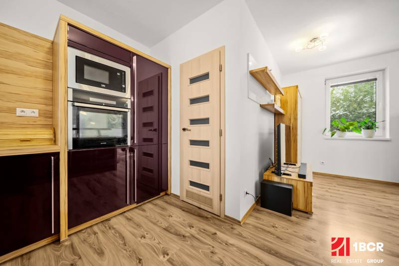 Kuchyně v rodinném domě s podlahou s dřevěným dekorem, moderními spotřebiči a plovoucími policemi.