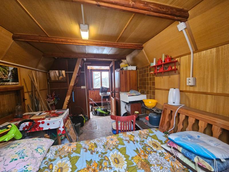 Interiér chaty s dřevěným dekorem, nábytkem a kuchyňskými potřebami.