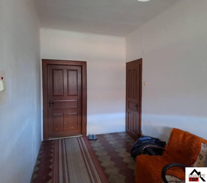 Interiér rodinného domu s dveřmi, křeslem a kobercovým běhounem.