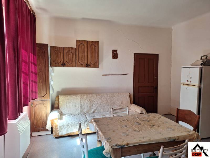 Interiér rodinného domu s pohovkou, jídelním stolem a dřevěnými skříňkami.