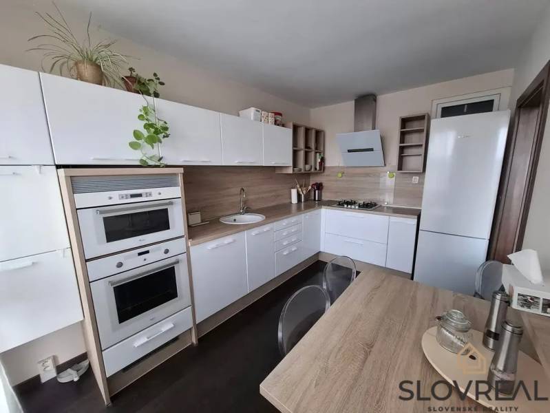 Kuchyně v 3-pokojovém bytě s bílou linkou a podlahou s dřevěným dekorem.